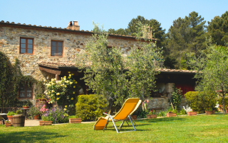 Maison champêtre, jardin taillé et végétation verdoyante.