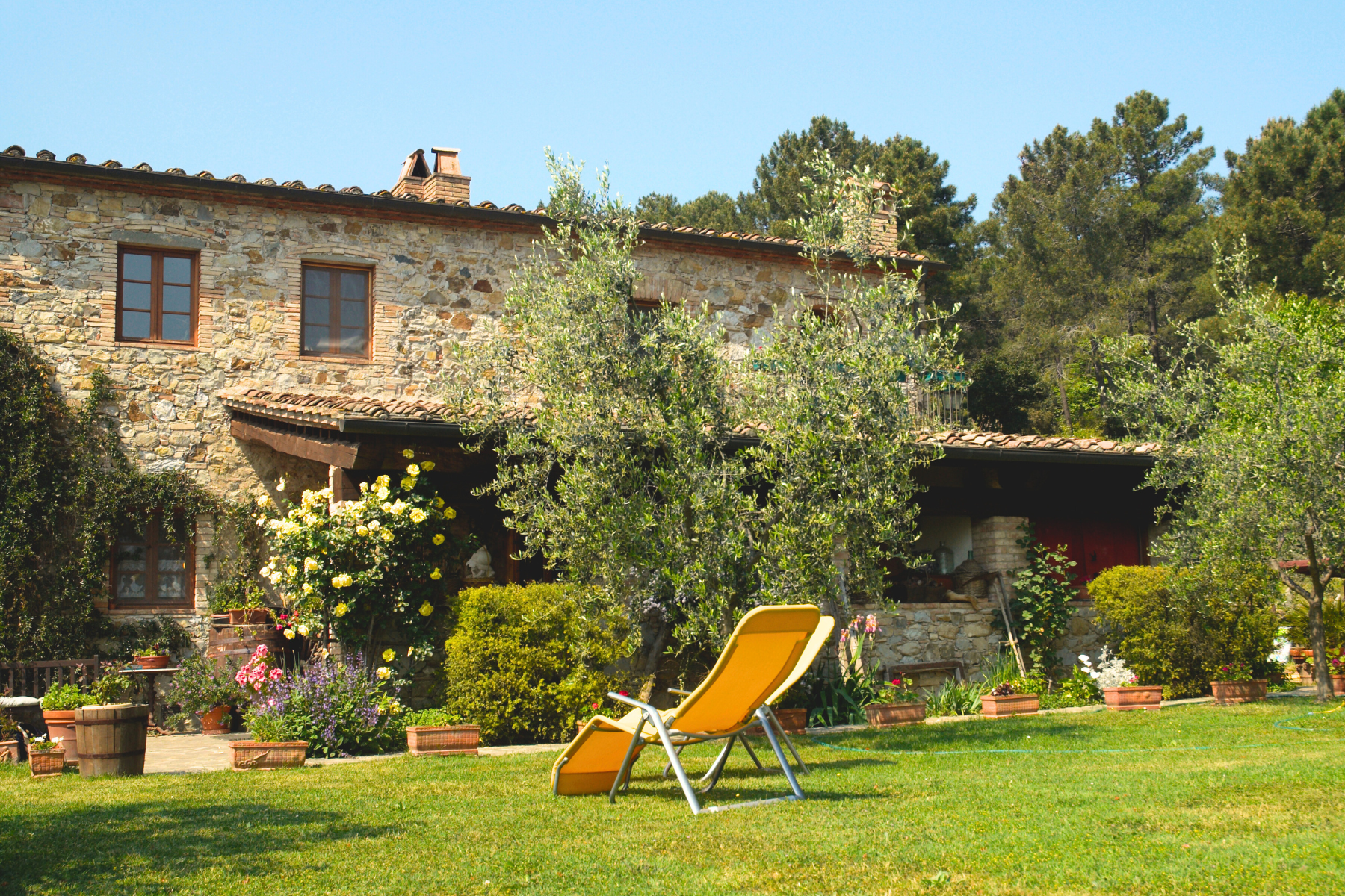 Maison champêtre, jardin taillé et végétation verdoyante.