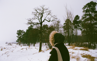 femme avec un manteau d'hiver se promenant dans la nature sous la neige