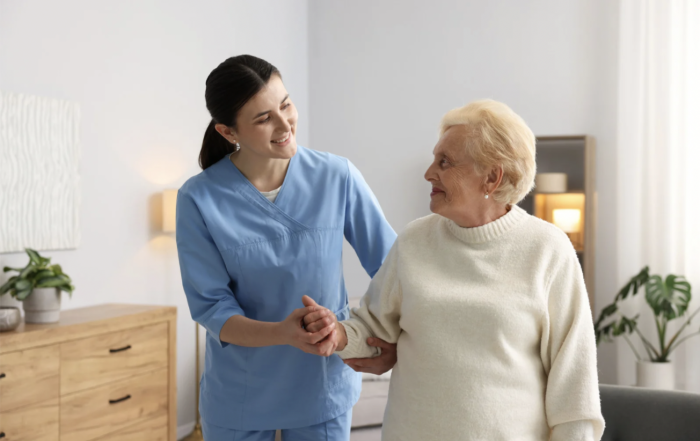 Une aide-soignante aide une patiente en intérieur