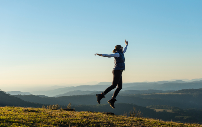 une femme qui saute en l'air dans un paysage naturel, qui montre un certain lacher prise
