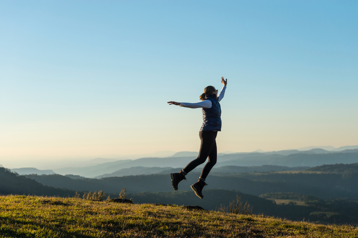 une femme qui saute en l'air dans un paysage naturel, qui montre un certain lacher prise
