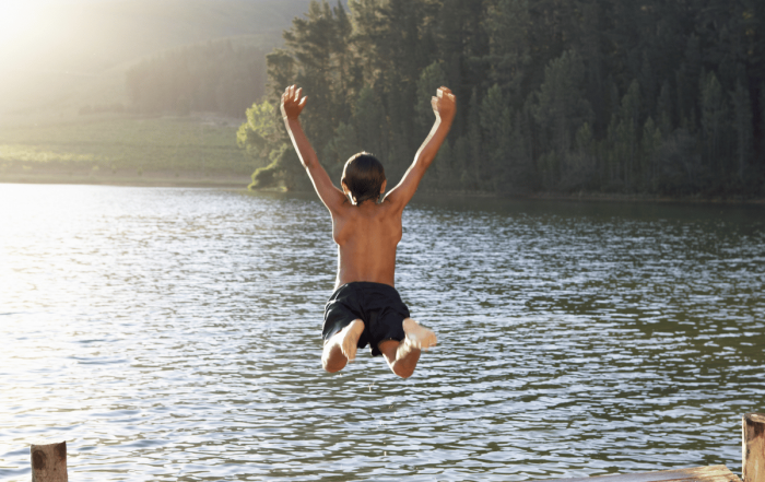 un enfant qui saute et se baigne dans un lac