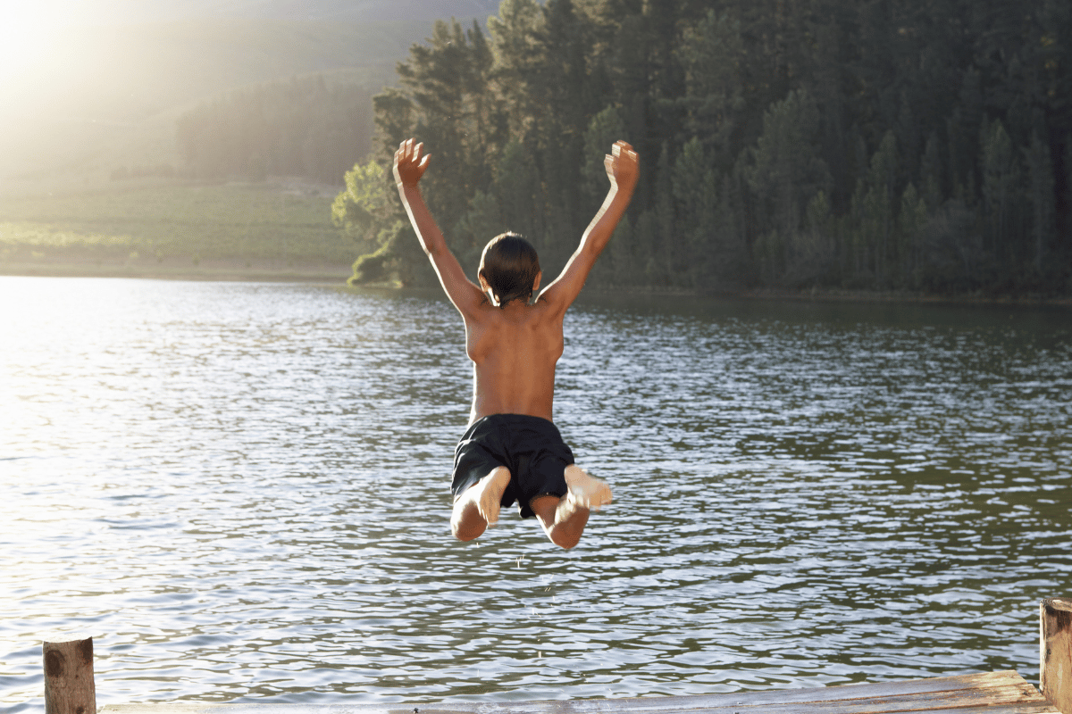 un enfant qui saute et se baigne dans un lac