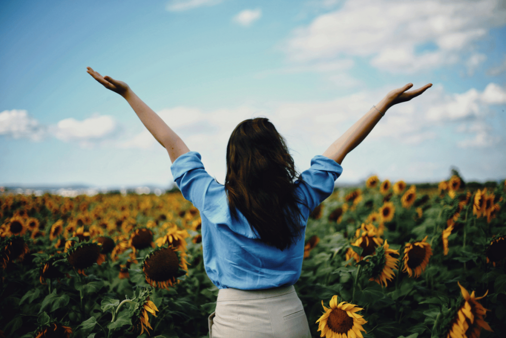 champs de tournesol avec une femme qui semble heureuse, les bras ouverts