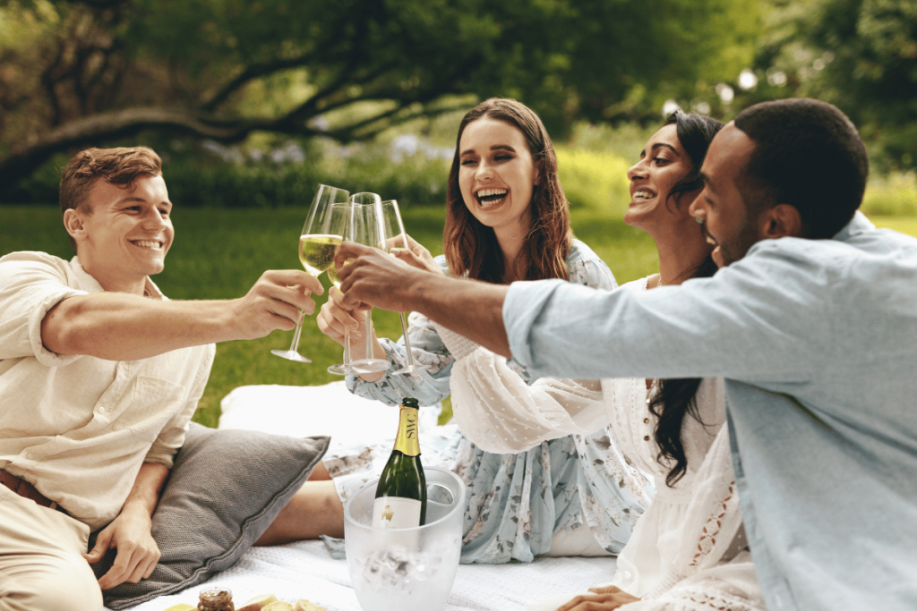 des amis qui prennent l'apéro dans un parc et boivent du champagne