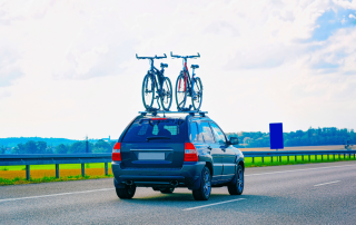 voiture avec des vélos sur le toit sur une route pour un départ de paris