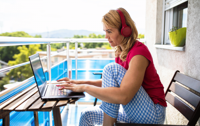 une femme qui télétravail depuis son balcon en été