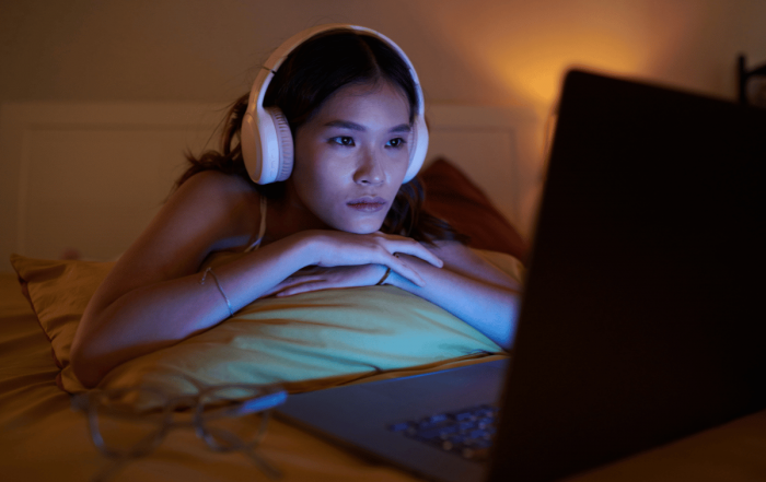 une femme qui regarde un documentaire sur son ordinateur depuis son lit avec un casque