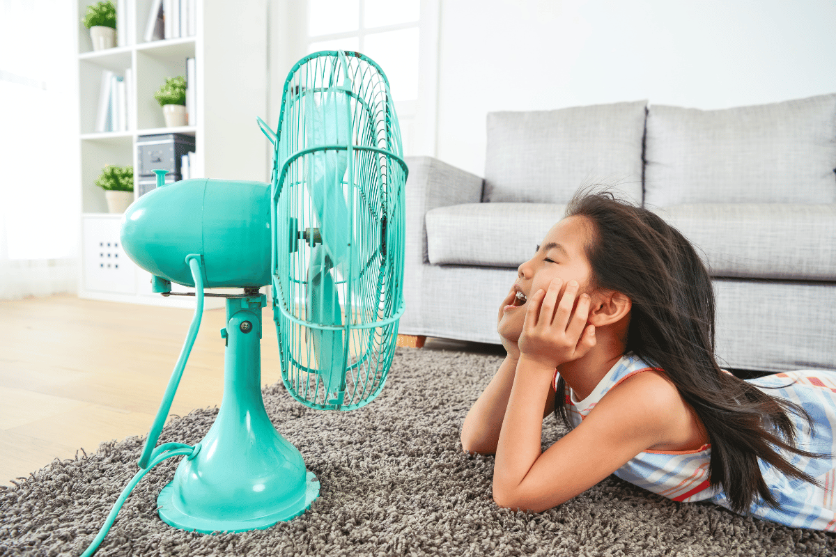 petite fille devant un ventilateur quand il fait trop chaud à l'interieur