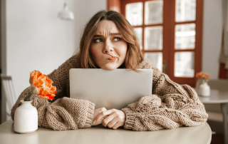 une femme qui semble déçue et hésitante devant son ordinateur