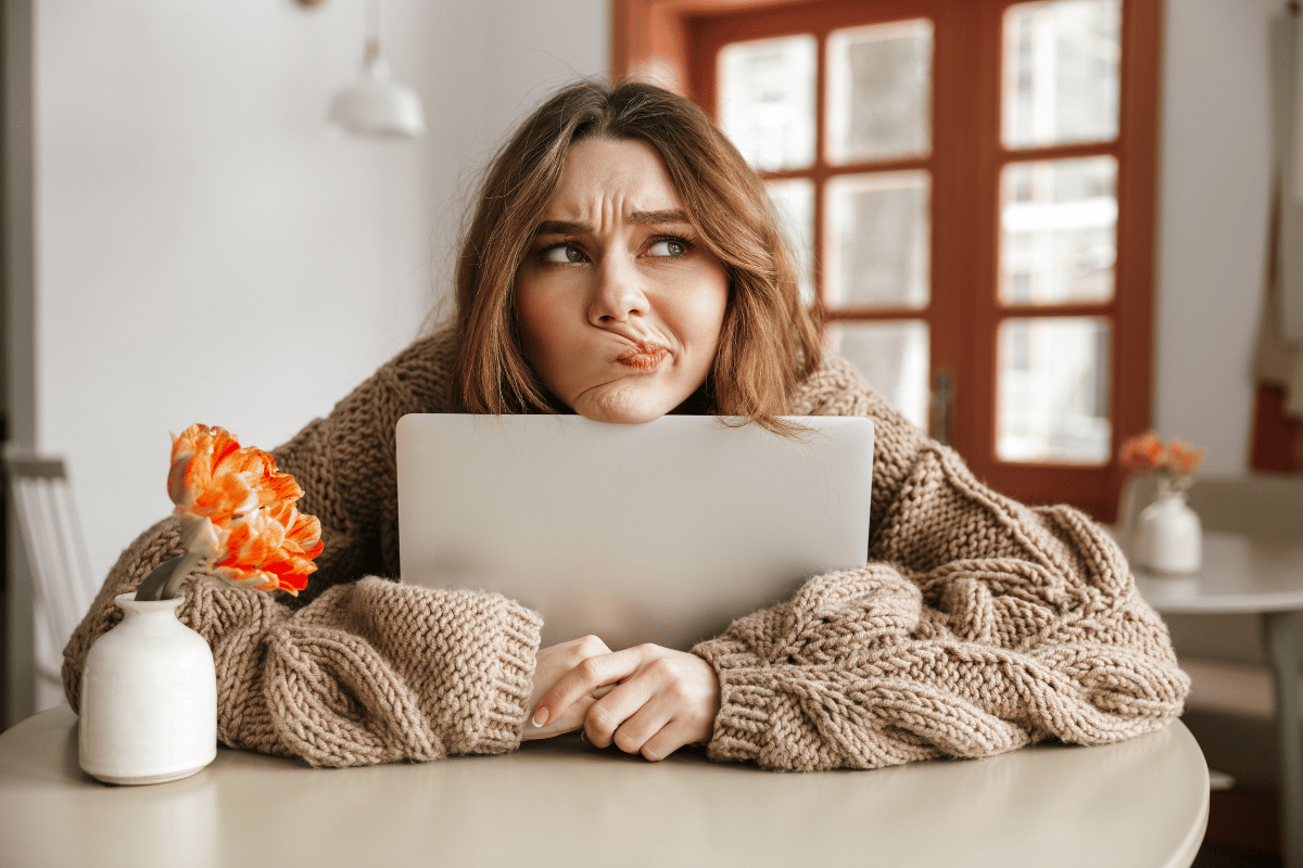 une femme qui semble déçue et hésitante devant son ordinateur