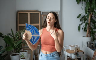 une femme avec un éventail qui tente de supporter la chaleur dans son appartement