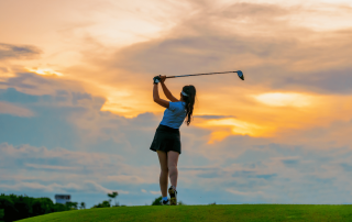 un femme qui joue au golf au coucher de soleil